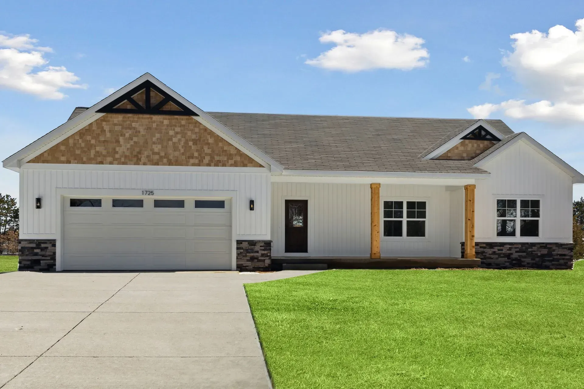 Single-story house with gray garage door, white siding, and a green lawn under a blue sky