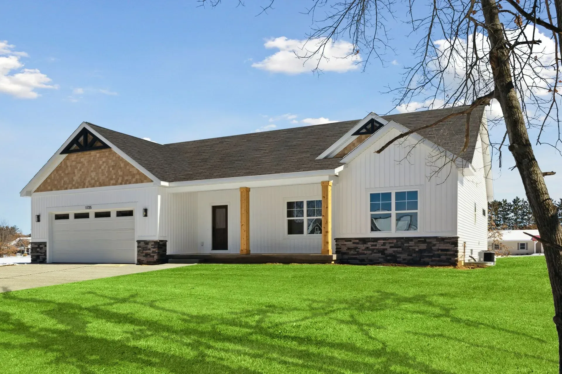 White suburban house with a garage, brown roof, and bright green lawn under a blue sky