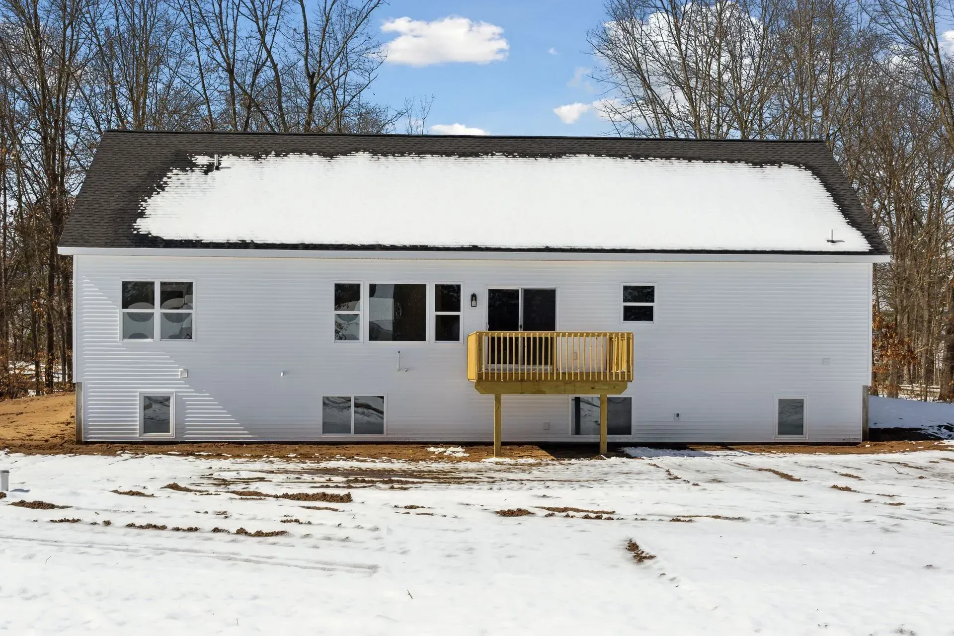 Snow-covered white house with a small wooden porch under a winter sky