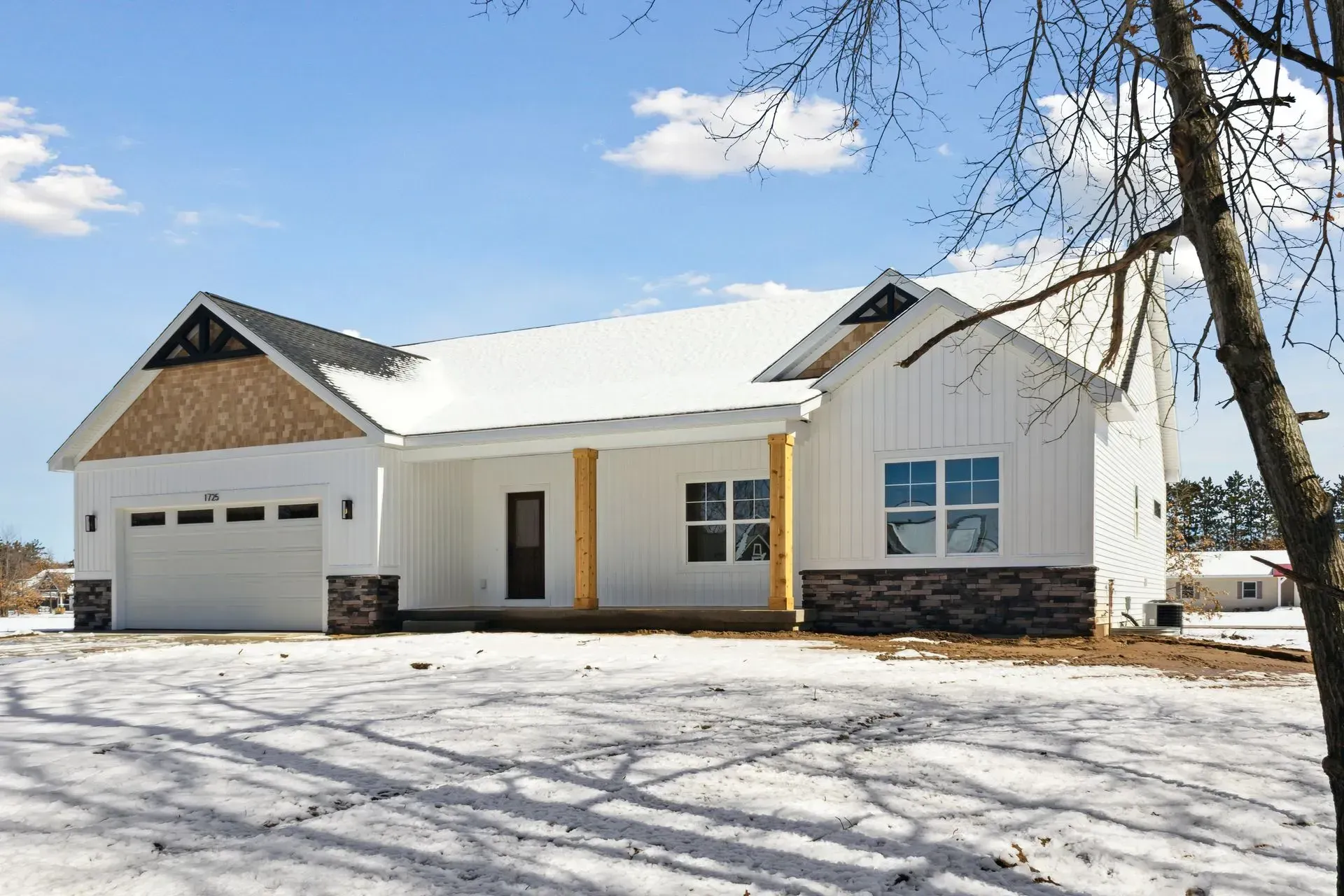 Snow-covered white house with attached garage under a blue sky