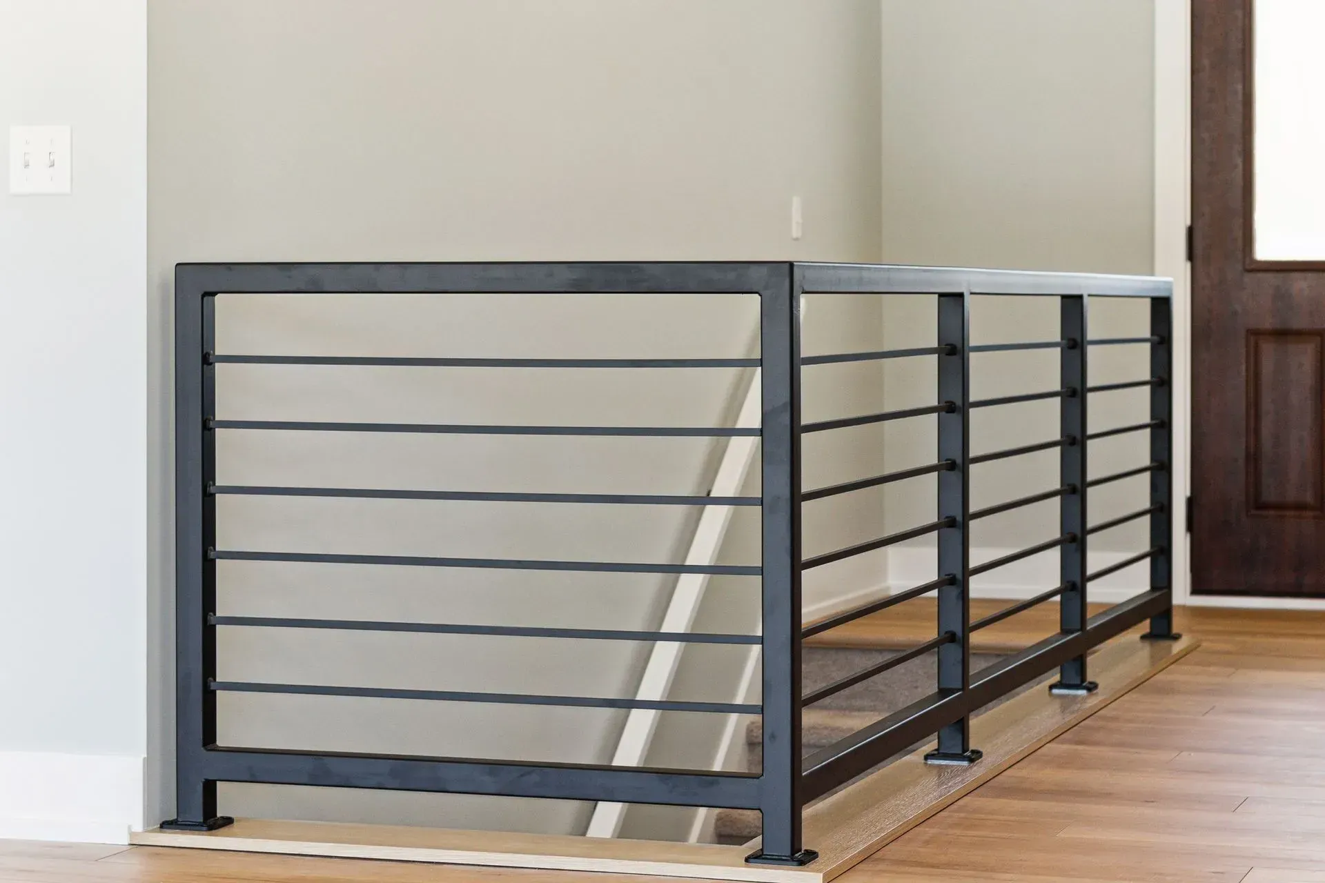 Gray metal stair railing beside wooden steps in a modern interior
