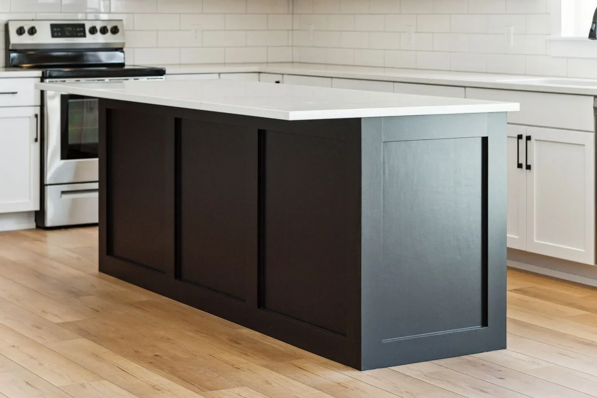 Dark kitchen island with white countertop in a bright modern kitchen