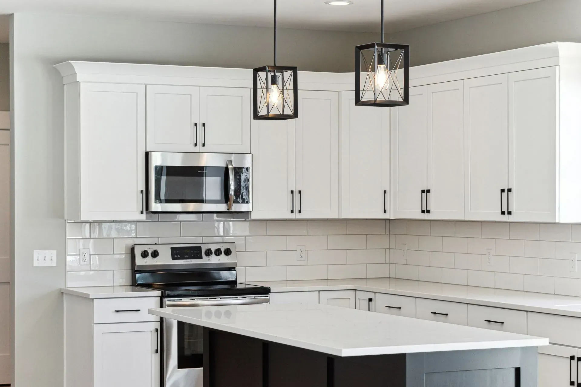 Modern kitchen with white cabinets, stainless appliances, subway tile backsplash, and island pendant lights