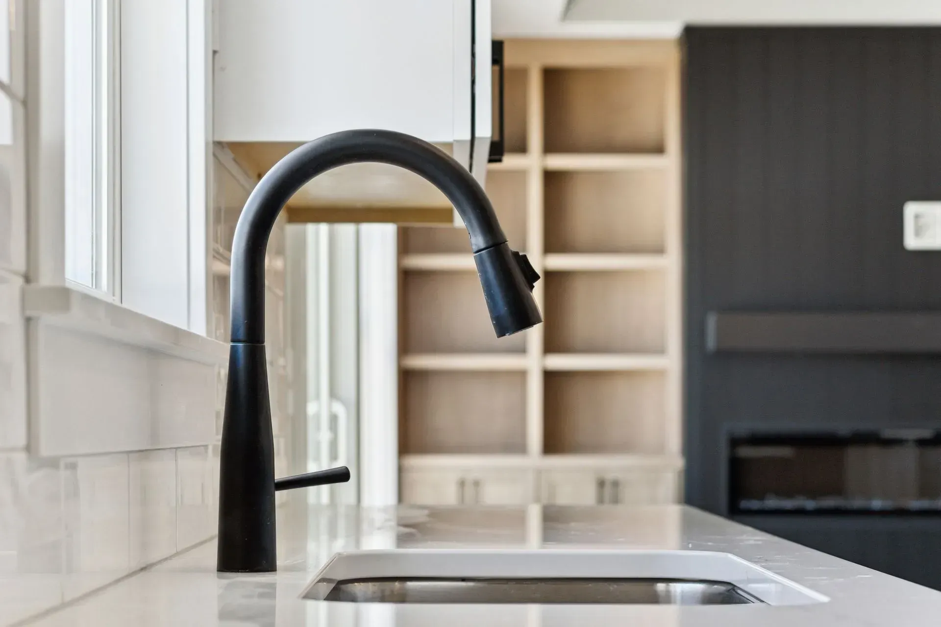 Modern kitchen sink with black gooseneck faucet and white cabinets