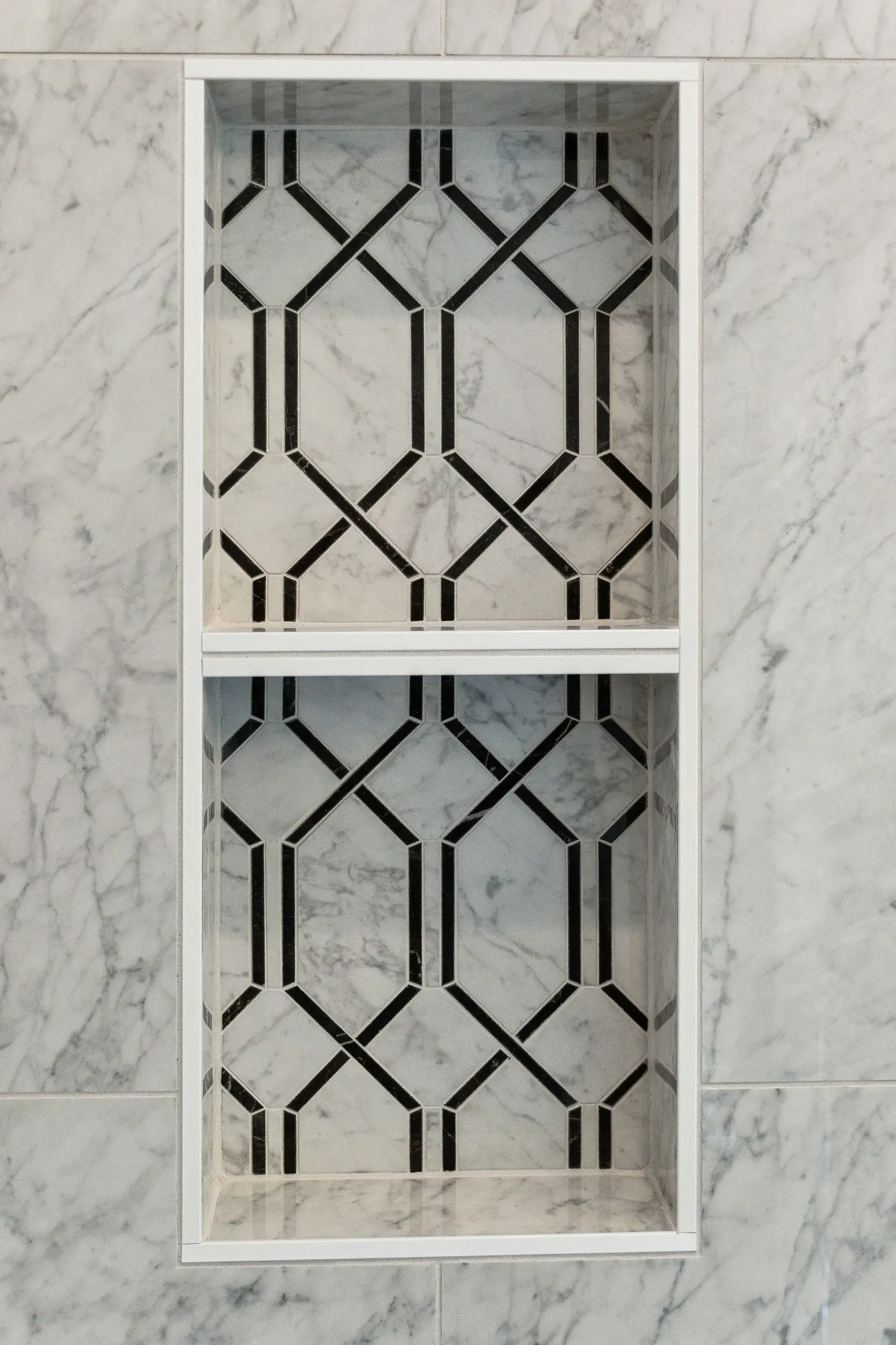 White-framed double decorative window with black geometric lattice on marble-patterned wall