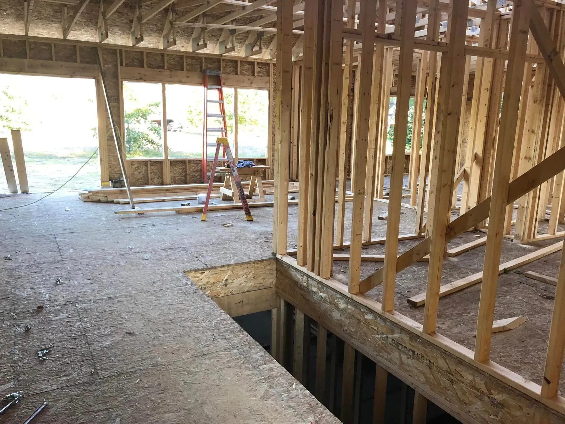 Interior of a house under construction with exposed framing and a floor opening in the foreground