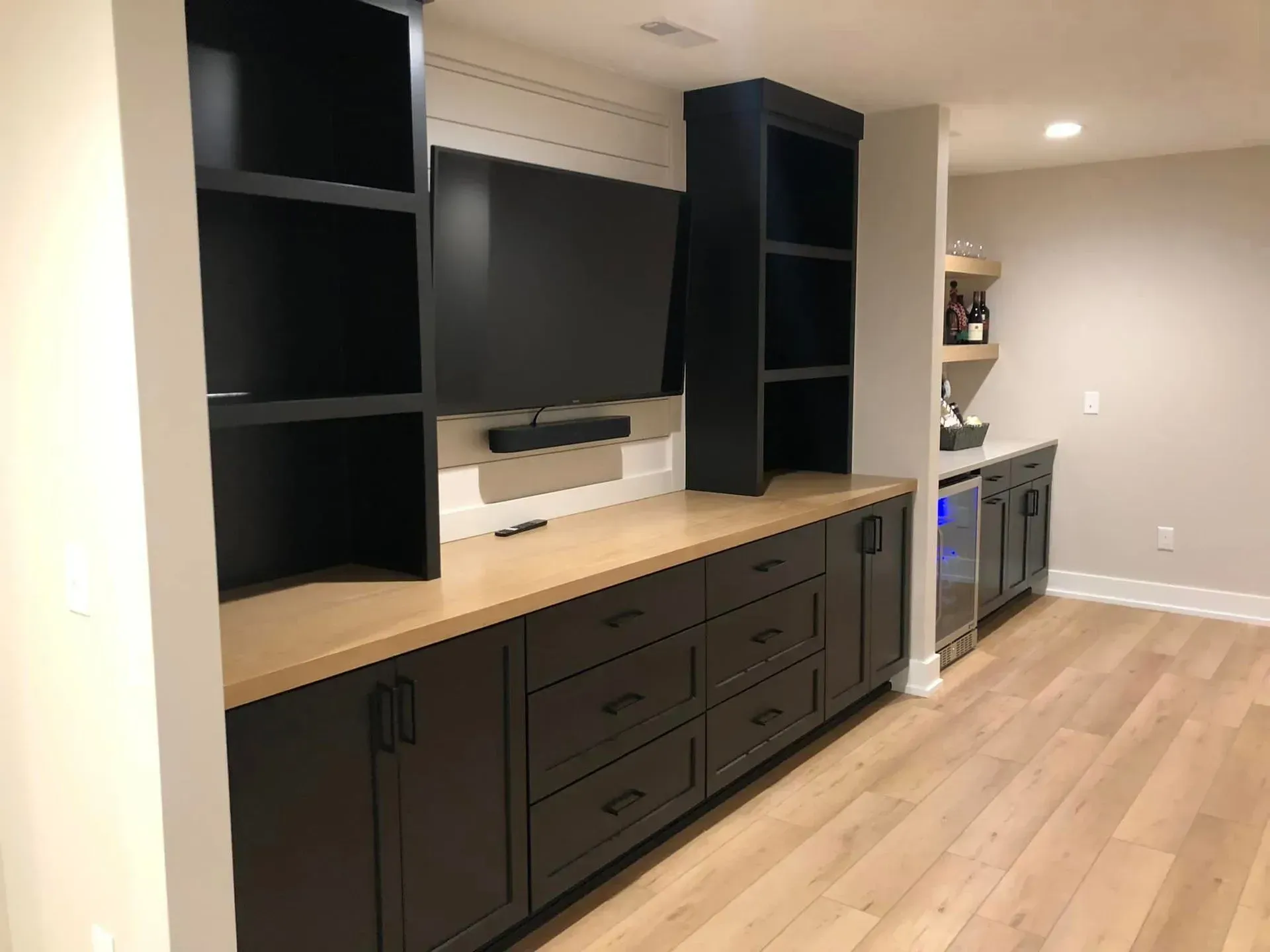 Built-in media wall with black shelves, large TV, and dark cabinets in a modern room