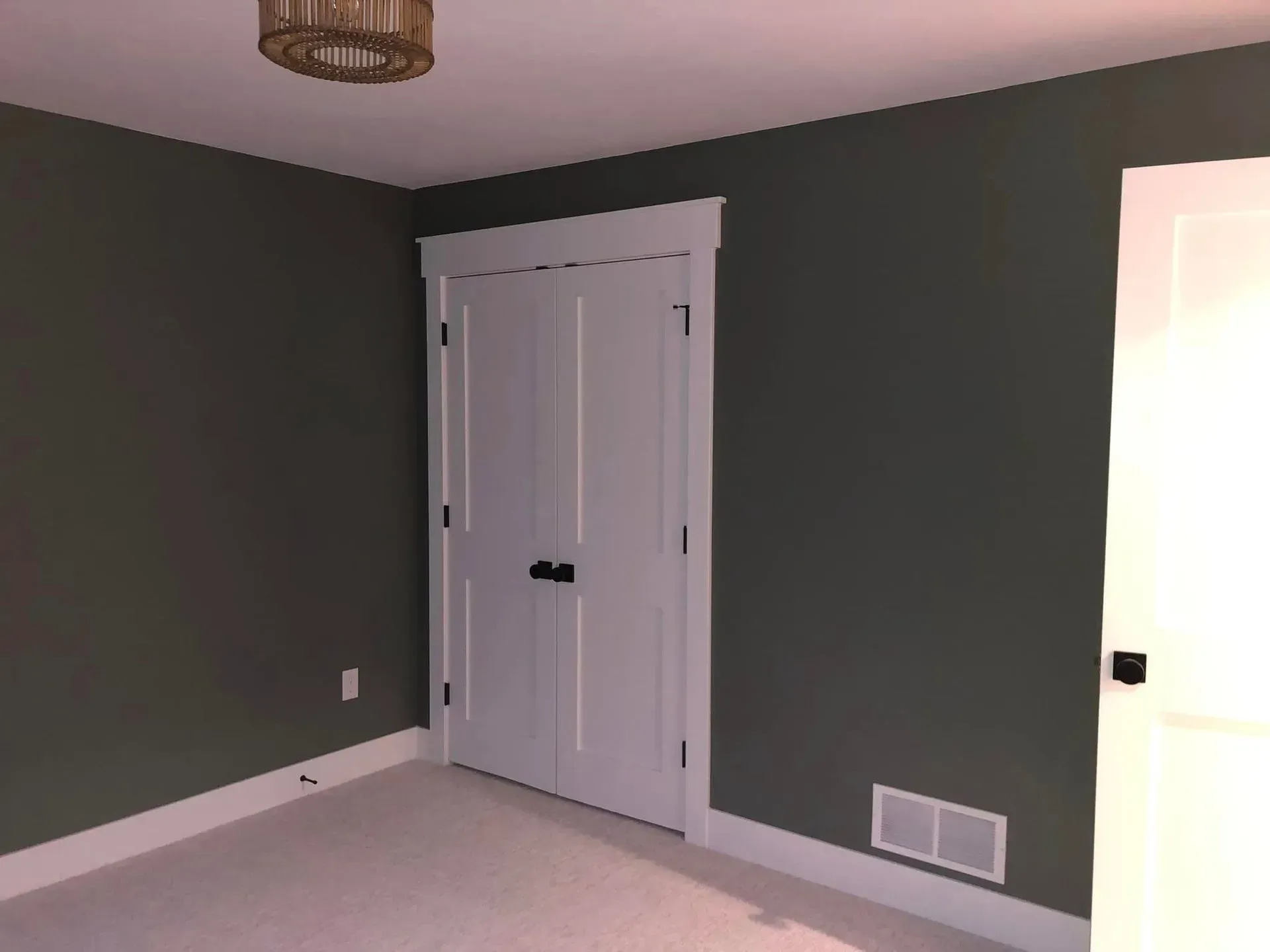 Empty room with dark gray walls, white double closet doors, and a ceiling light fixture.