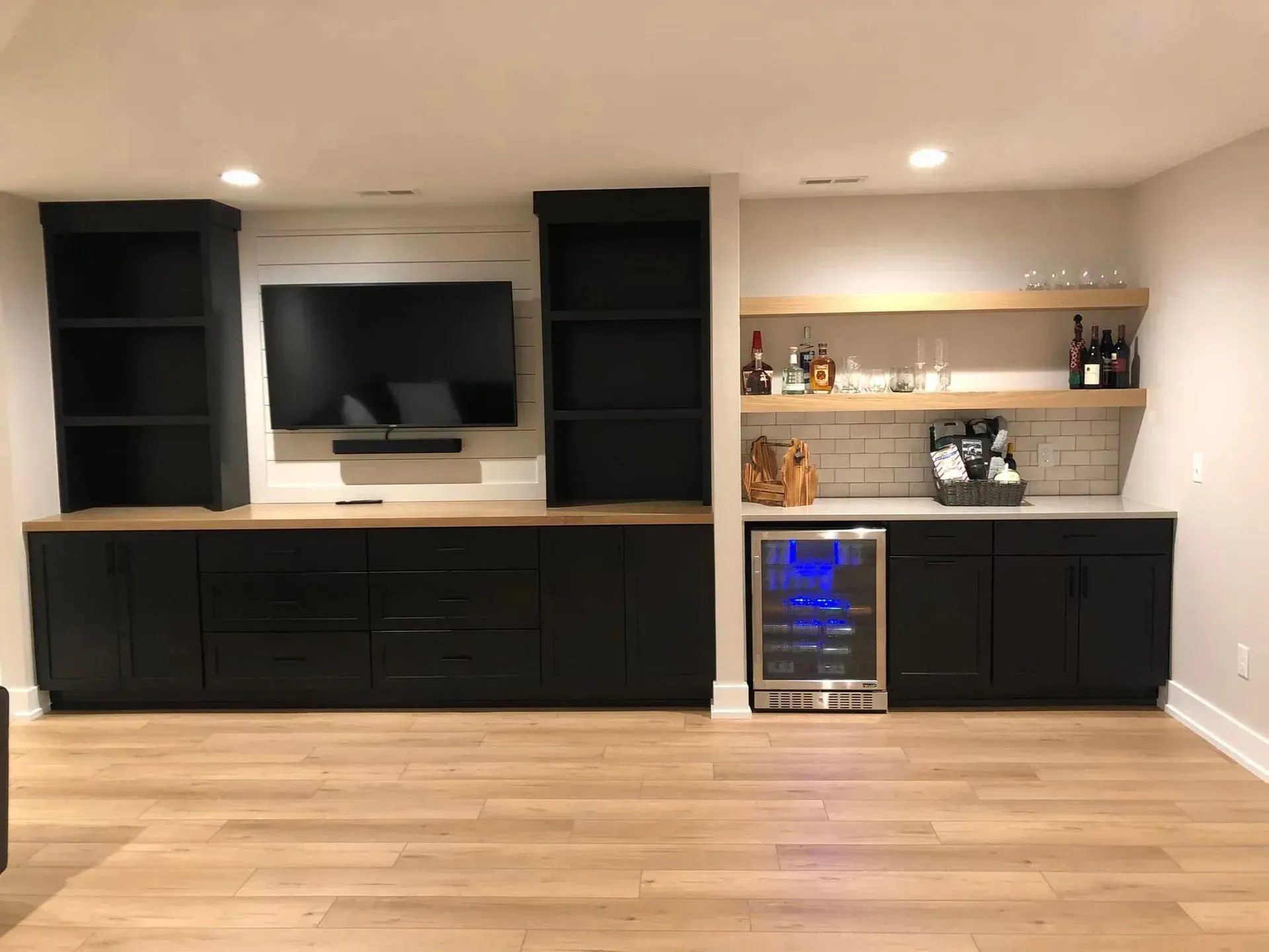 Built-in media wall with black cabinets, TV, and shelving in a modern room