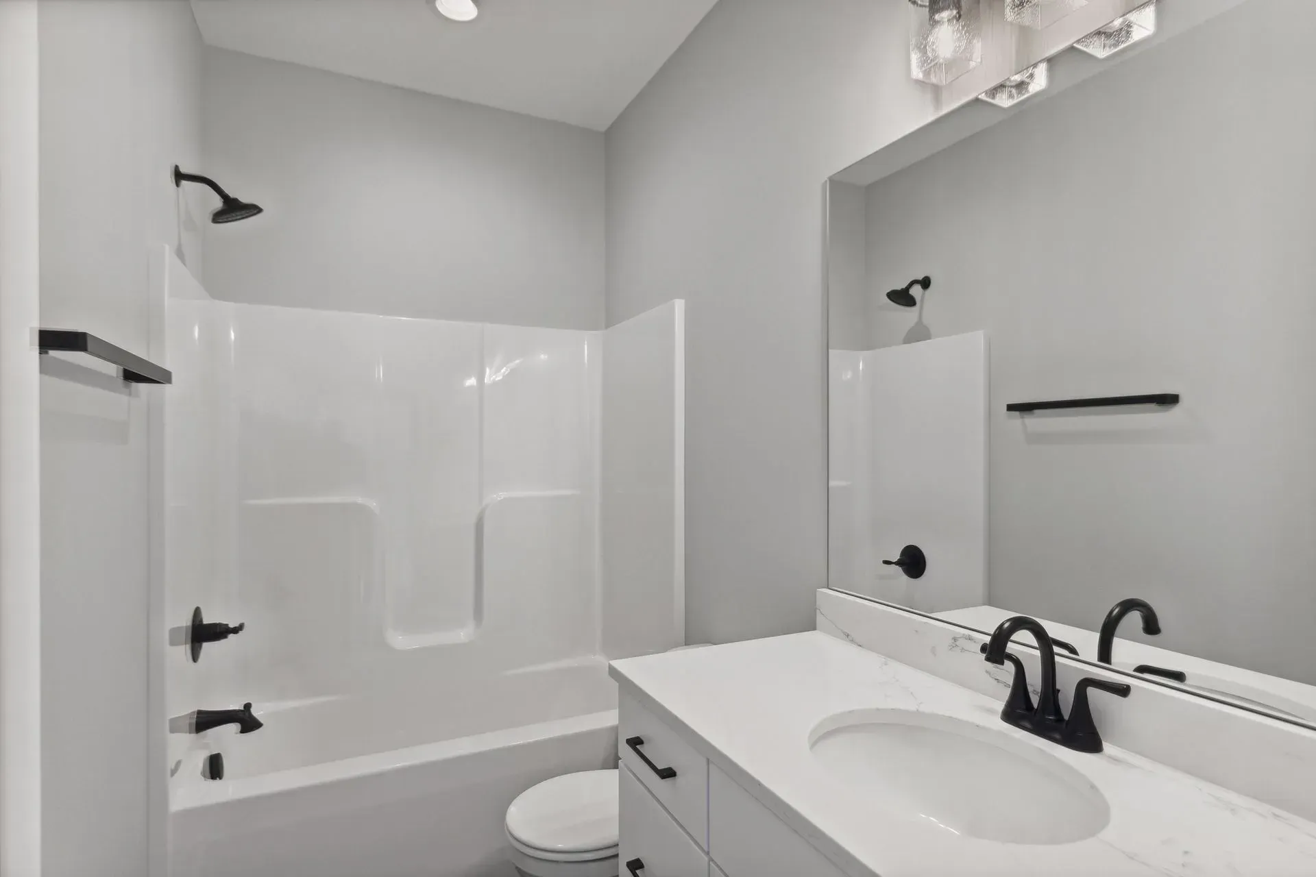 Bright white bathroom with tub-shower, black fixtures, and vanity with sink and mirror