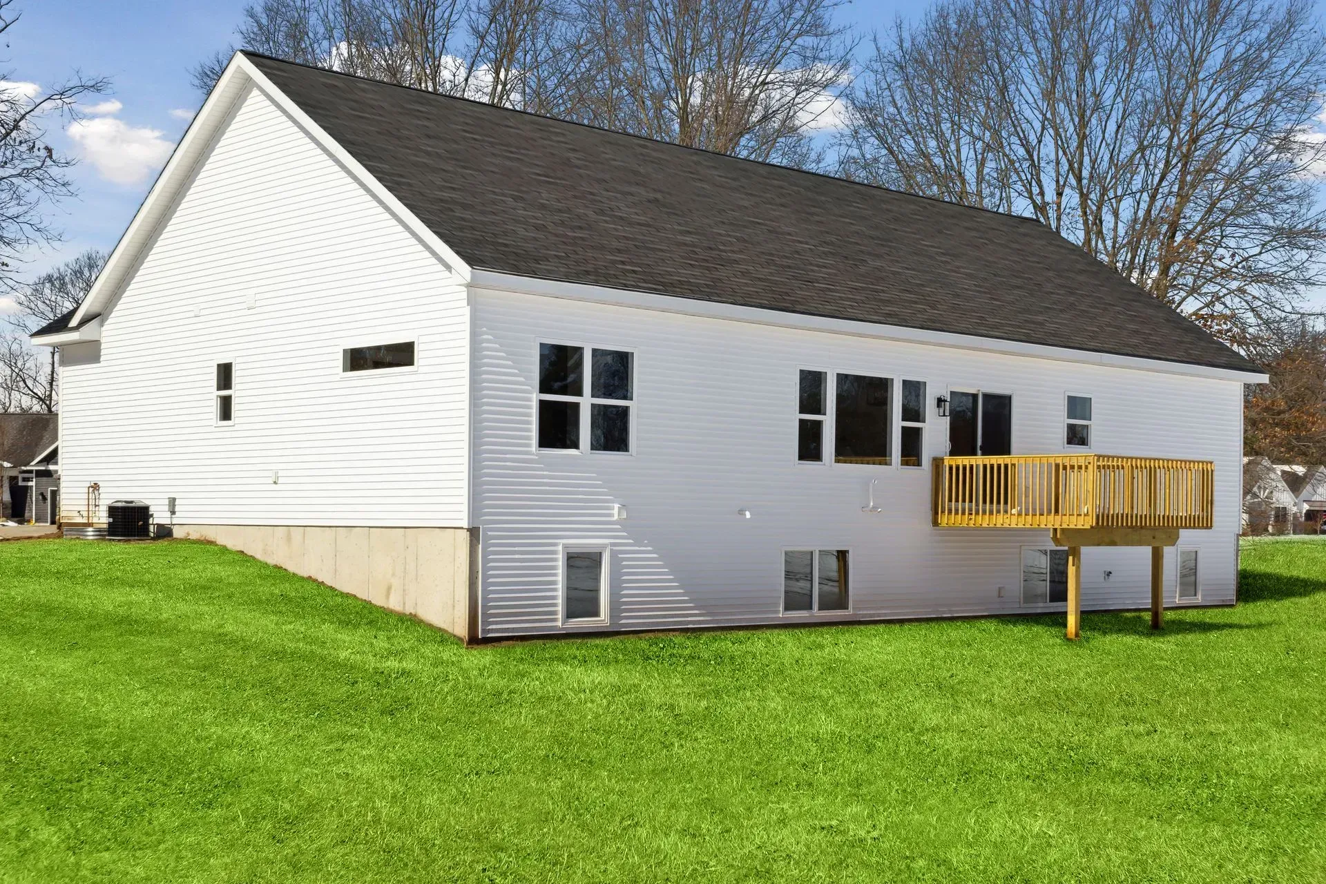 White house with a yellow deck on a grassy lawn under a blue sky