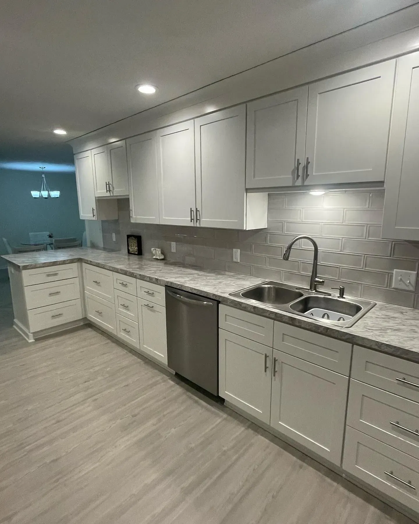 Bright modern kitchen with white cabinets, gray countertops, stainless dishwasher, and subway tile backsplash