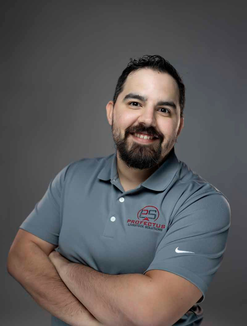 Man with a beard in a gray polo shirt, arms crossed, smiling. Gray background.