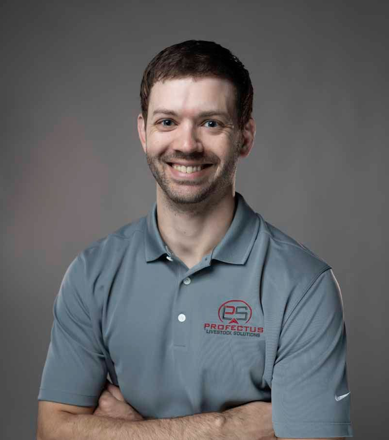 Smiling man in a gray polo shirt with crossed arms, standing in front of a gray background.