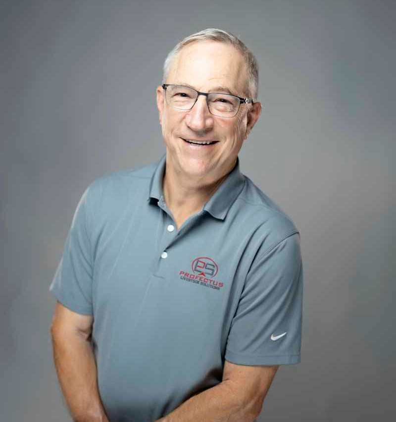 Man wearing glasses and a grey polo shirt smiles at the camera, arms crossed. Gray background.