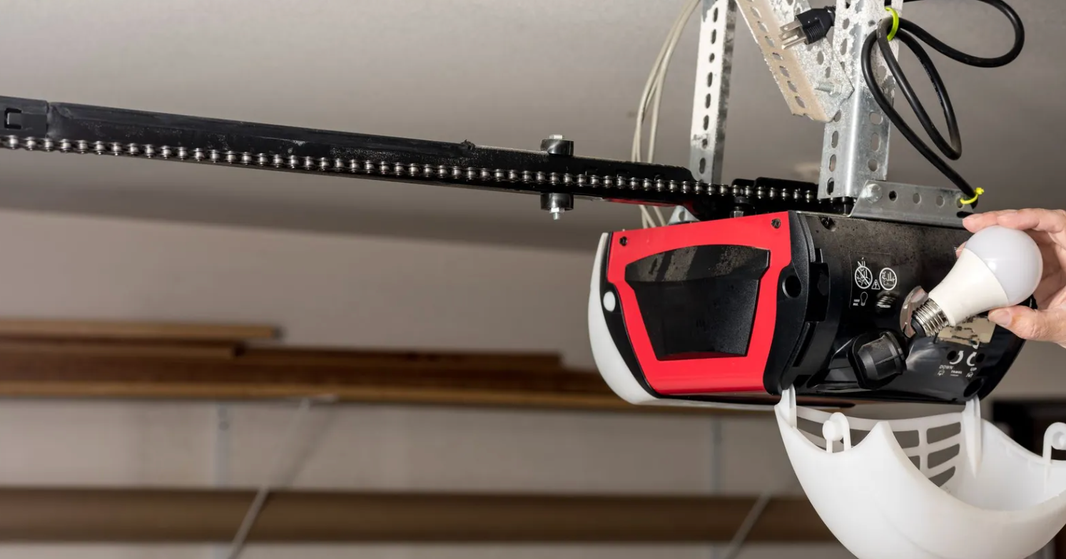 LiftMaster garage door opener mounted on a concrete wall, with wiring and electrical outlet.