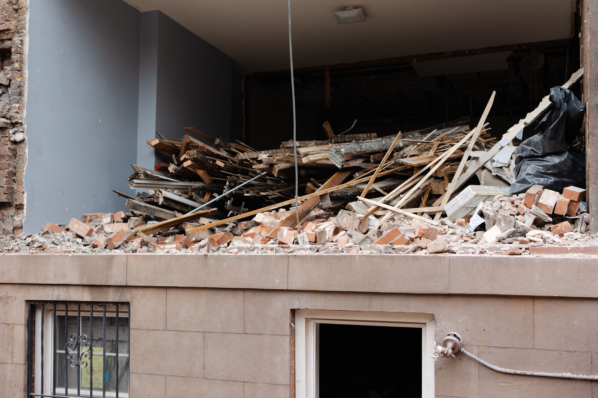 Collapsed building interior with rubble and broken wooden beams spilling onto the facade.