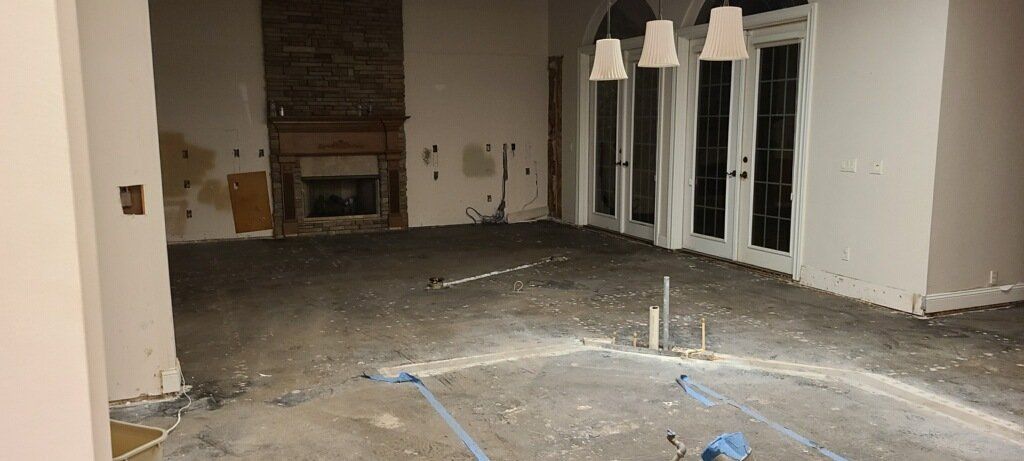 Empty living room with unfinished flooring, a fireplace, and hanging pendant lights