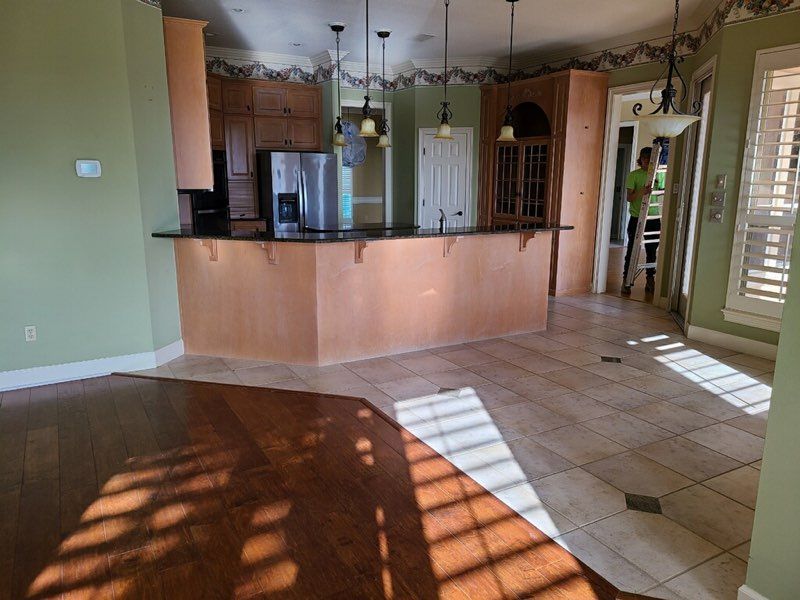 Open kitchen and dining area with tile floor, wood cabinets, pendant lights, and sunlight through windows