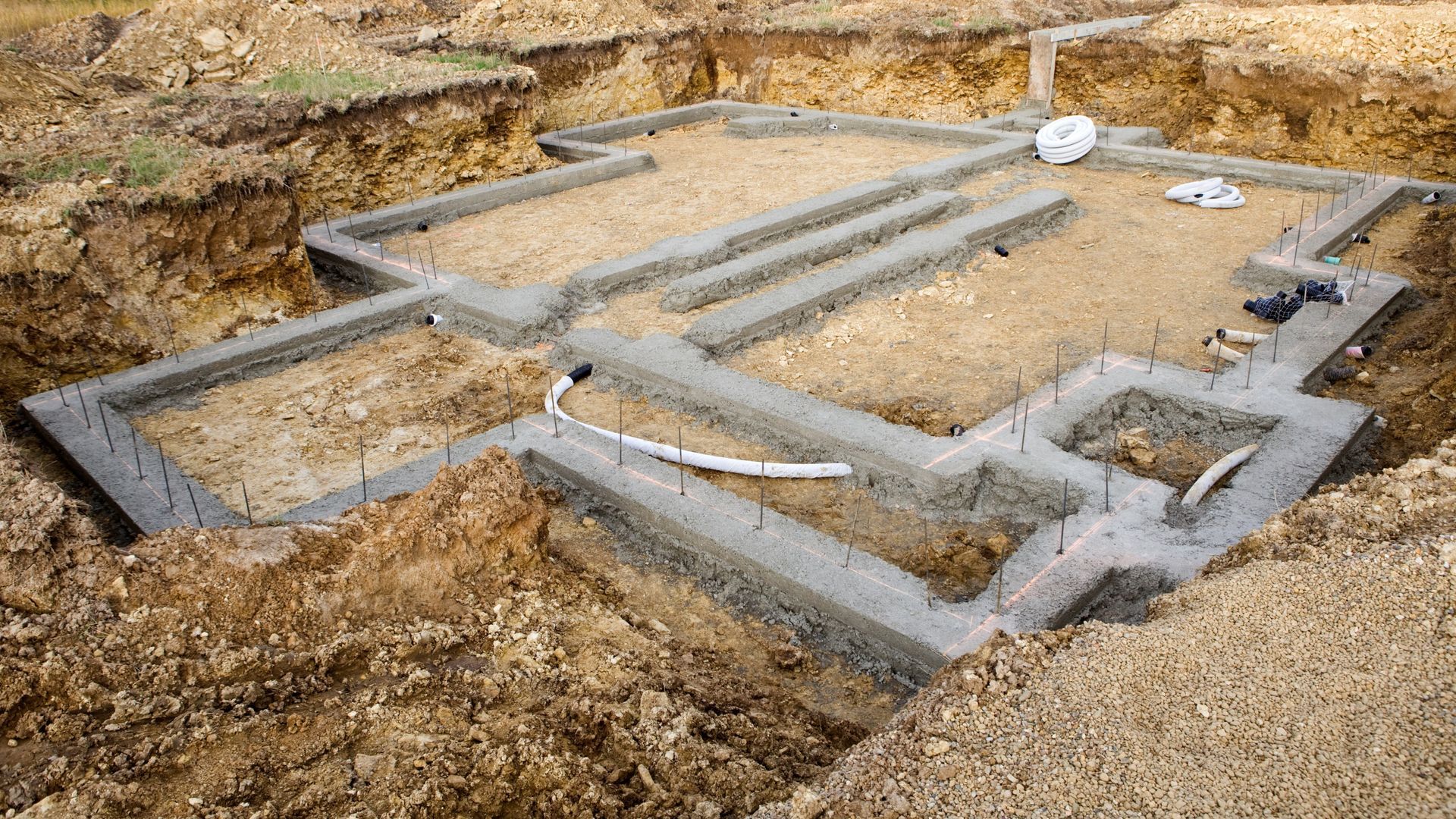 Concrete foundation outlines at a construction site on dirt ground
