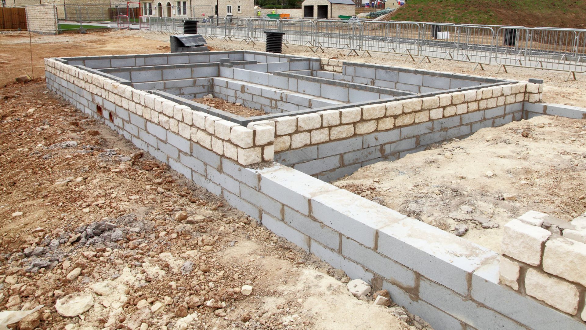Partially built cinder block foundation on a dirt lot at a construction site