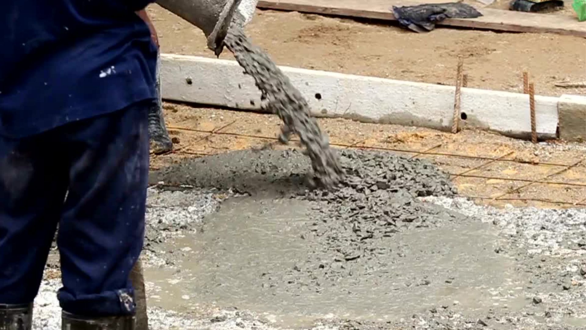 Man with blue pants guiding concrete being poured into foundations from a Volumetric Concrete wagon from PureMix, Rochdale.