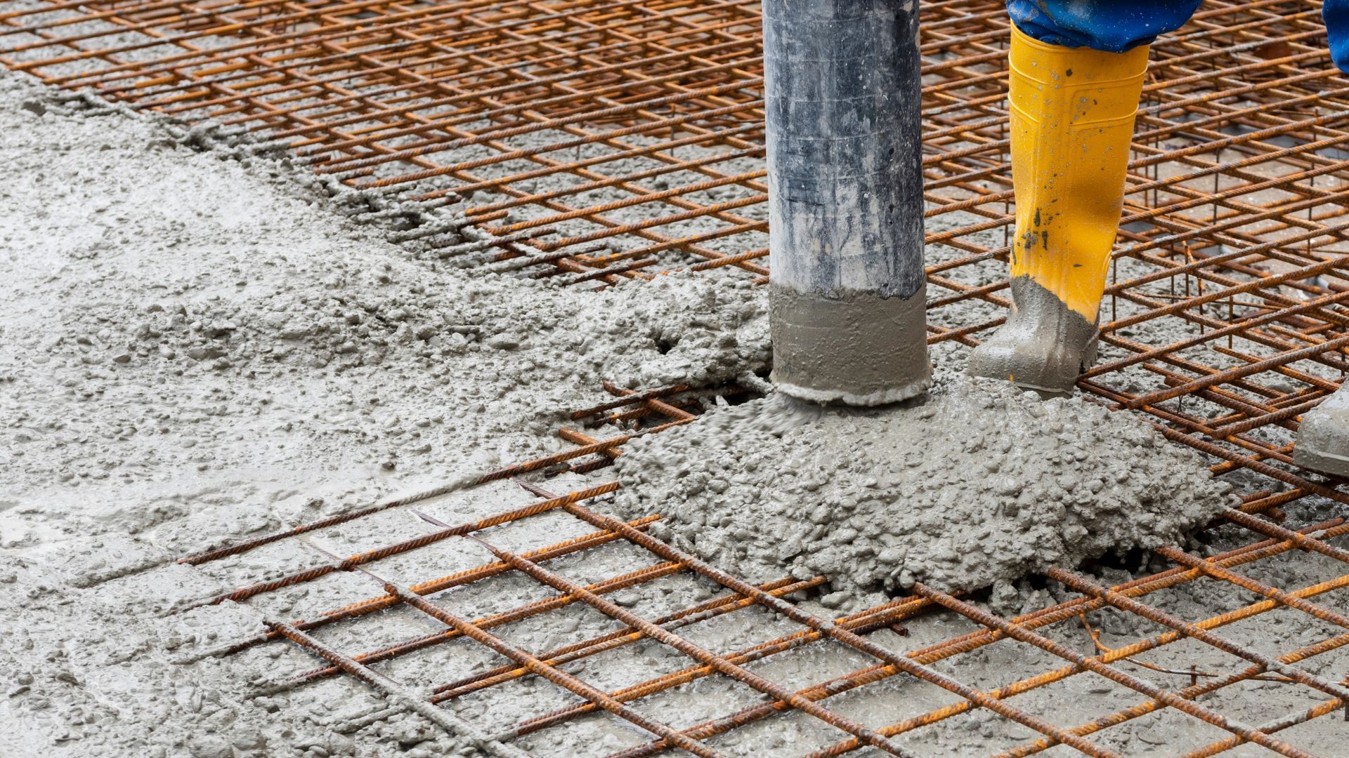 Man with yellow wellies pumping concrete supplied form PureMix Ready Mix Concrete, Rochdale, into reinforced foundations.