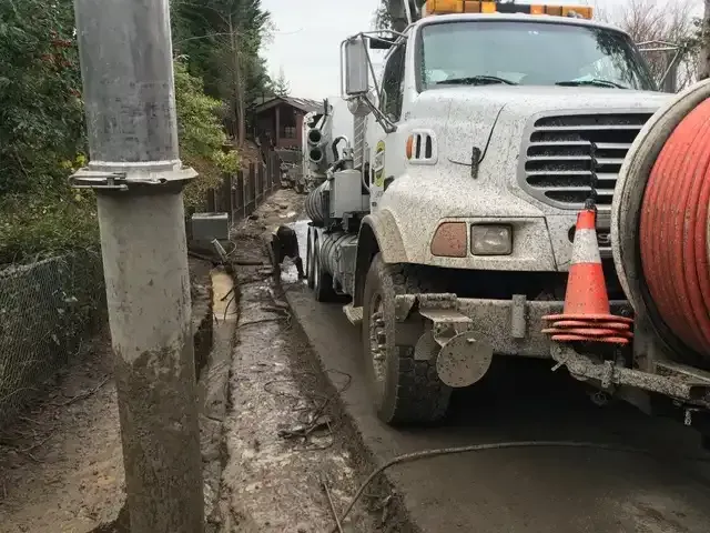 Hydrovac truck working in wet winter ground beside a utility pole in Buckley, WA