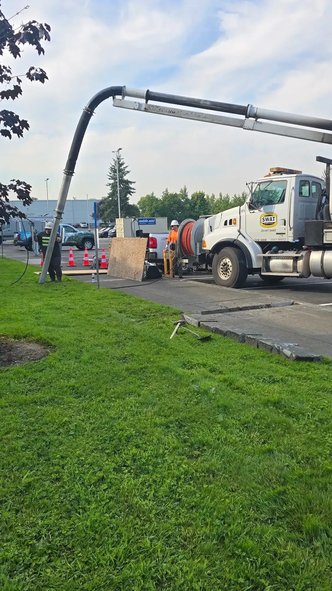 Hydro excavation slot cut through turf and concrete next to a parking lot, with no damage to the surrounding surface