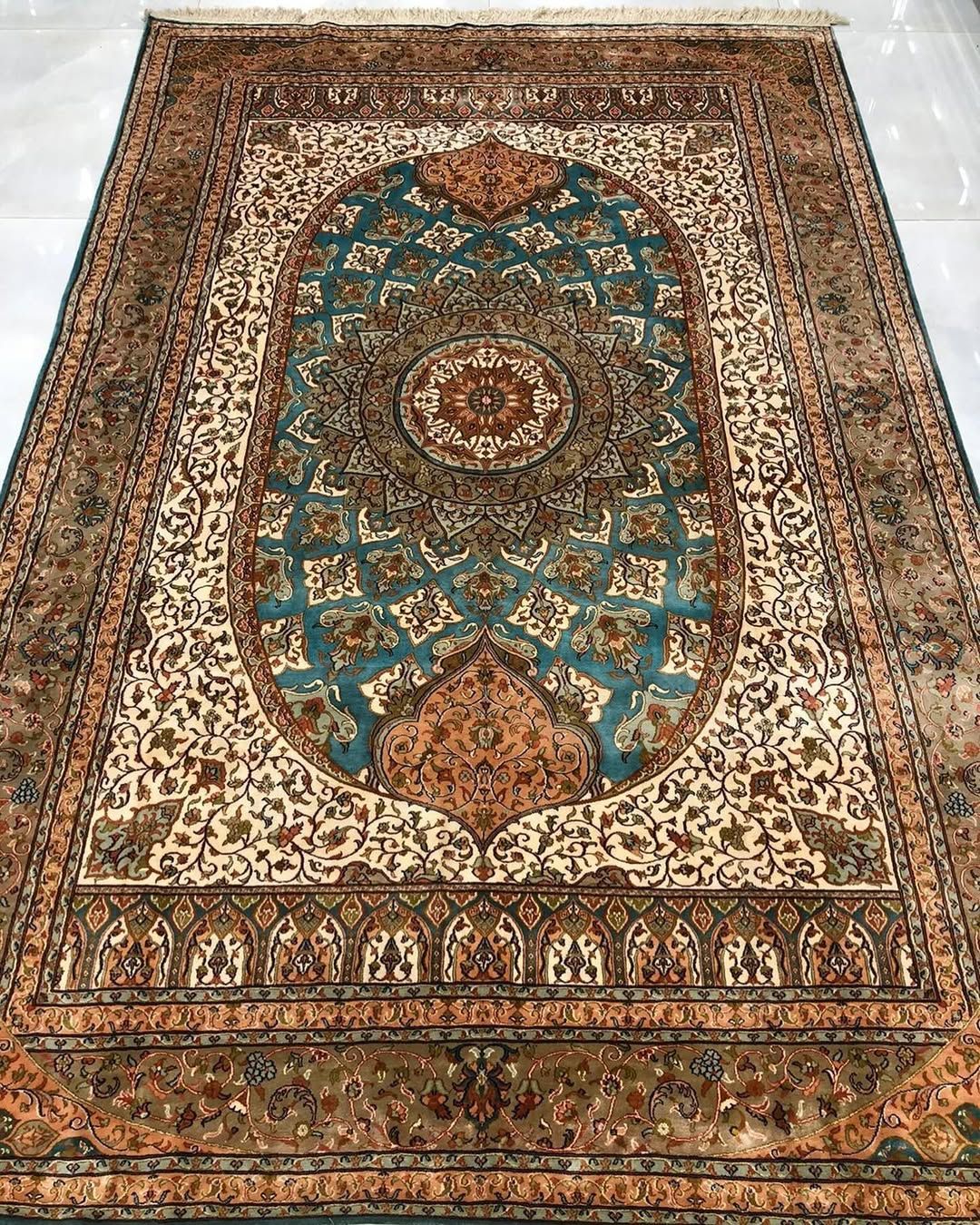 Ornate, rectangular rug with a teal and ivory central design, surrounded by a detailed border.