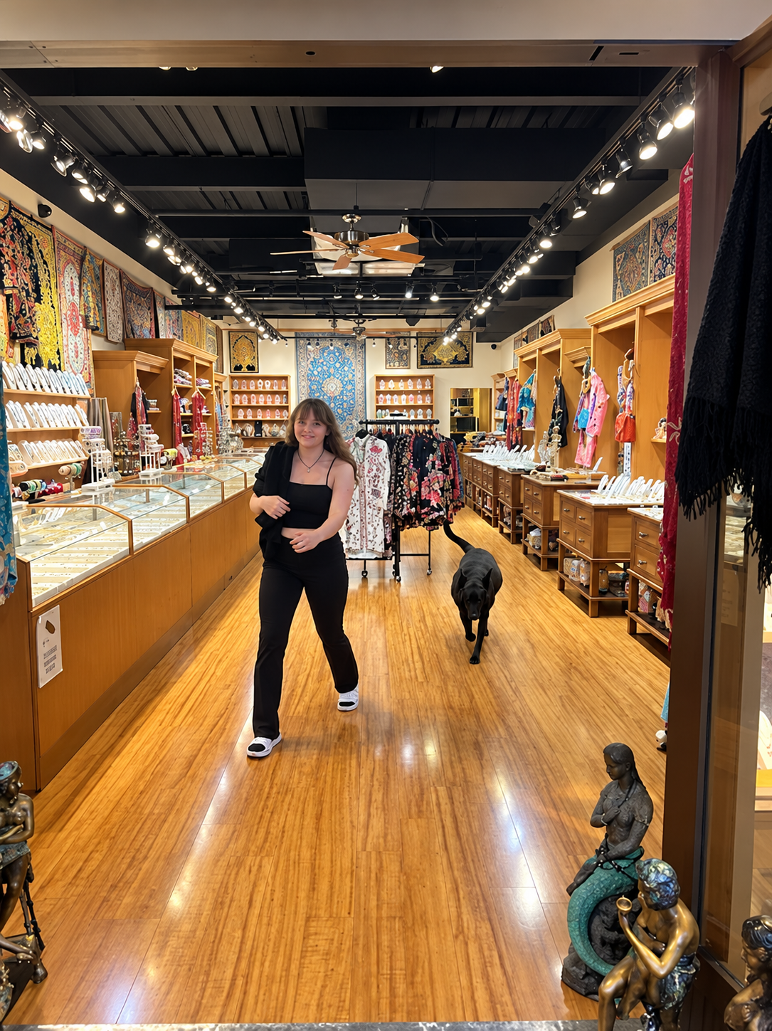 Woman and dog walk inside a store with jewelry displays and wood flooring.