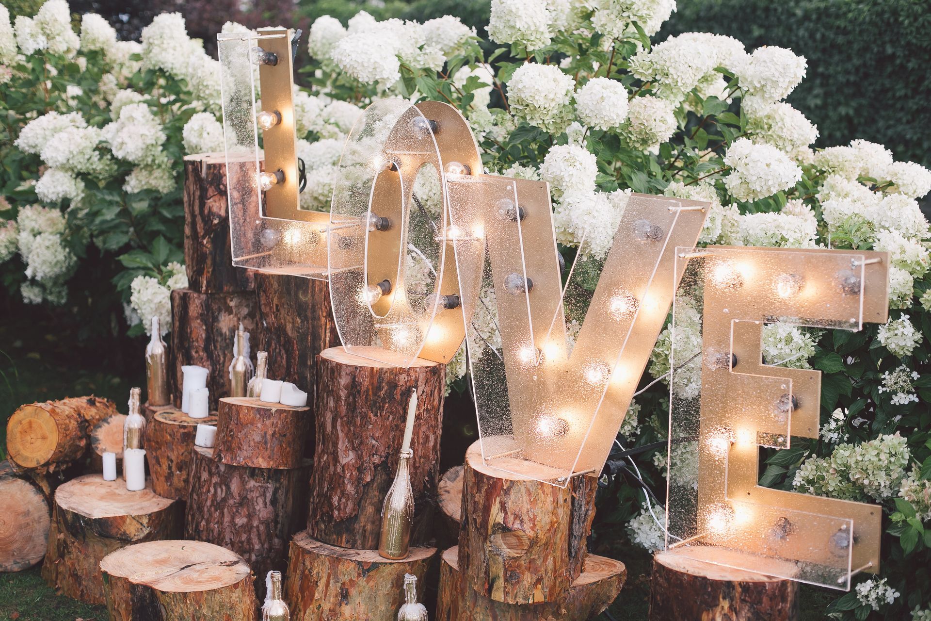A wooden sign that says love is sitting on top of a pile of logs.