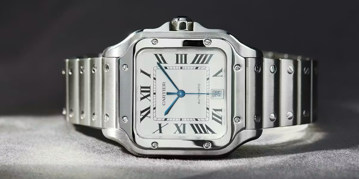 Silver Cartier Santos watch with a white face and Roman numeral hour markers on a light background.