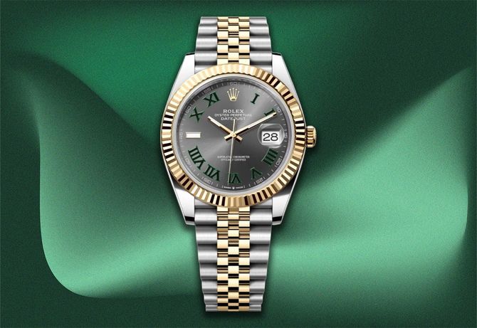 Rolex Datejust watch with a gold and silver band, set against a green fabric background.