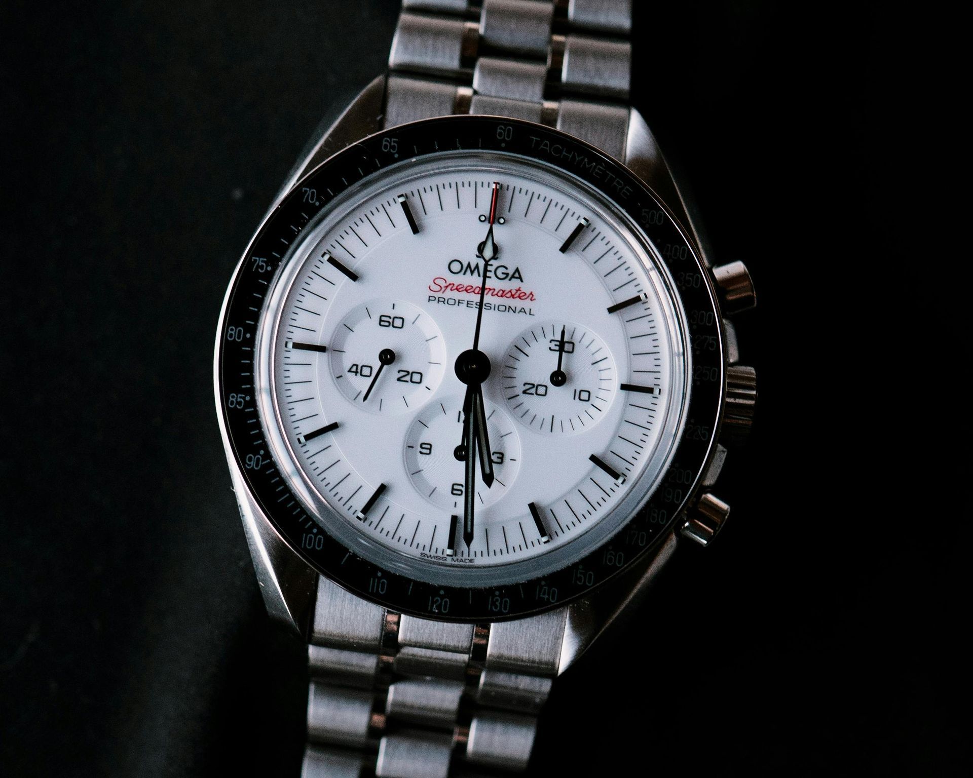 Silver Omega Speedmaster Professional watch with white face, black bezel, and stainless steel band.