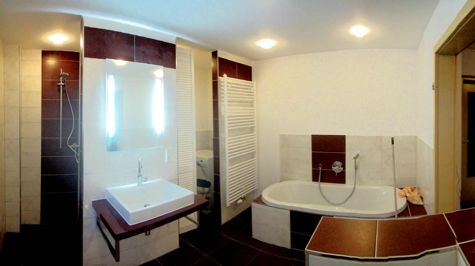Modernes Badezimmer mit weißen und braunen Fliesen, Badewanne und Waschbecken.