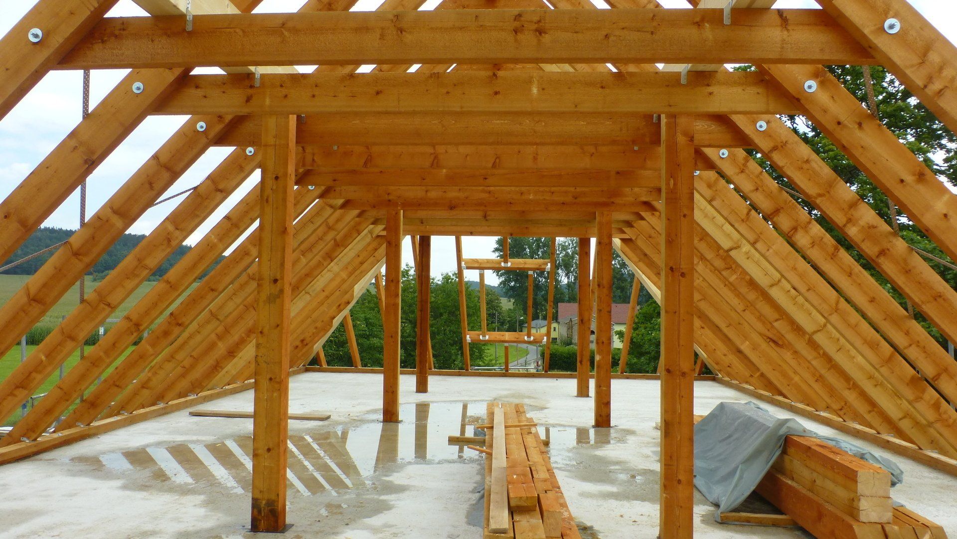 Im Bau befindliches hölzernes Dachgerüst mit sichtbaren Balken und Stützen.