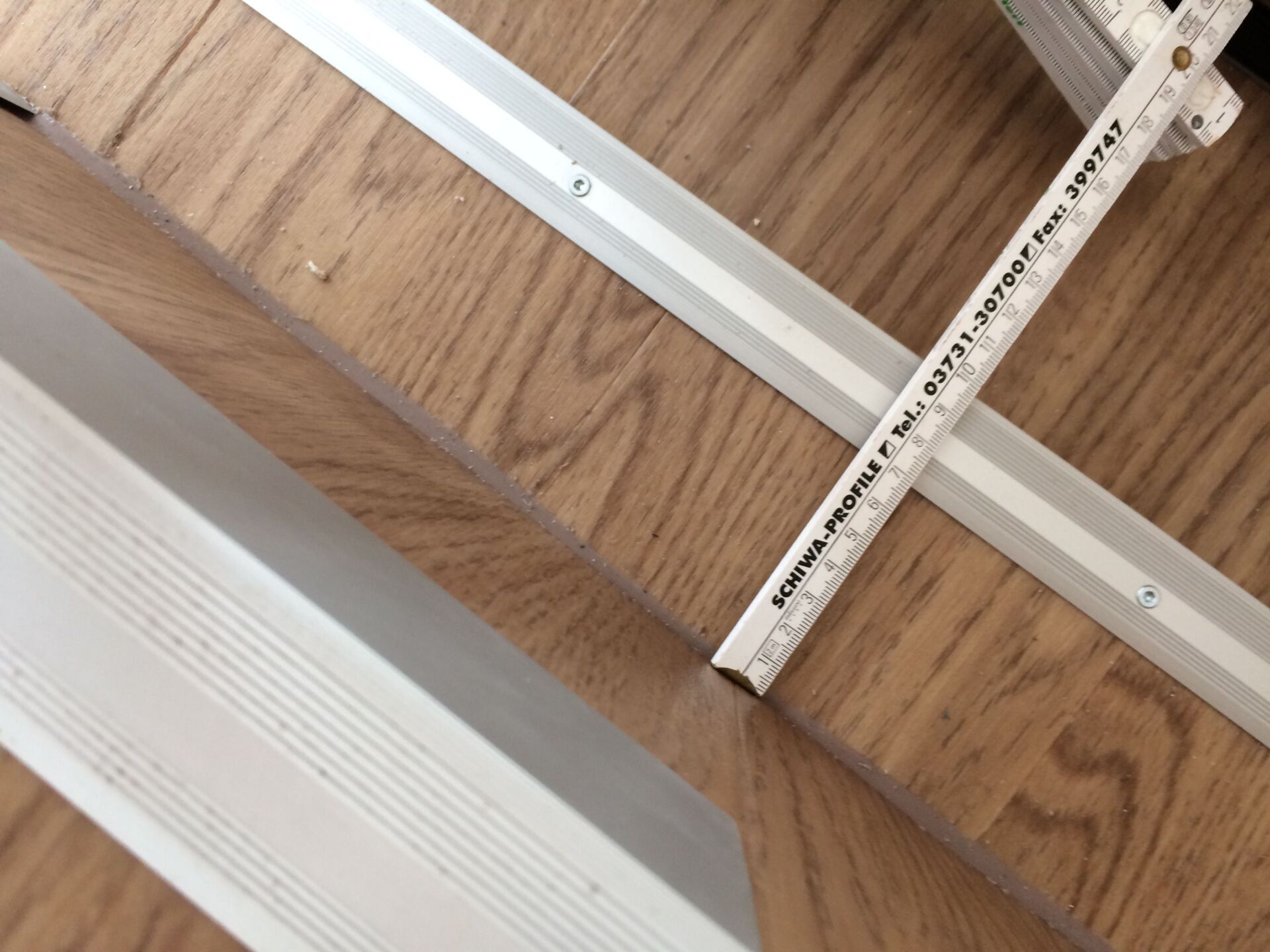 Holzboden mit Metalleinfassung und ein darauf liegendes Klapplineal.