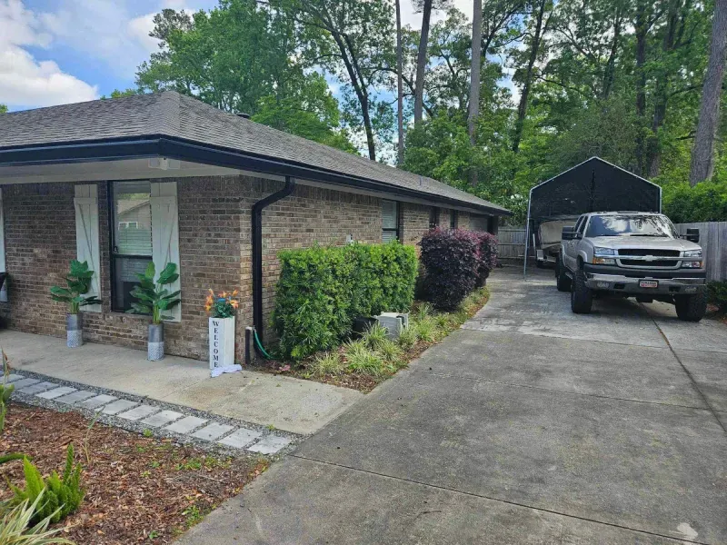 A white truck is parked in front of a brick house.