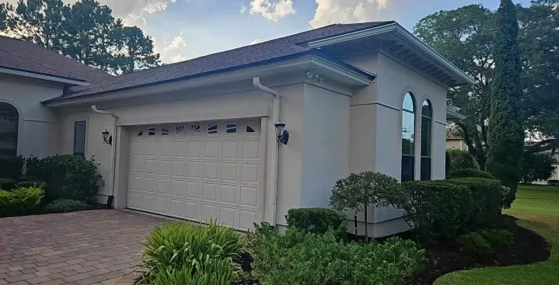 A white house with a garage and a driveway in front of it.