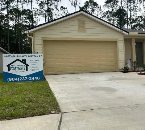 A house with a sign in front of it that says gutters