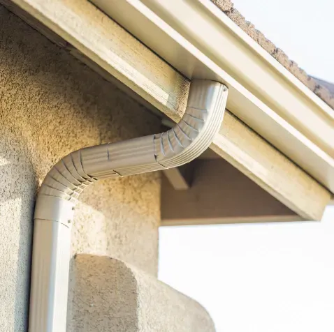 A close up of a gutter on the side of a house.