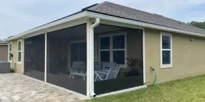 A house with a screened in porch and patio furniture.