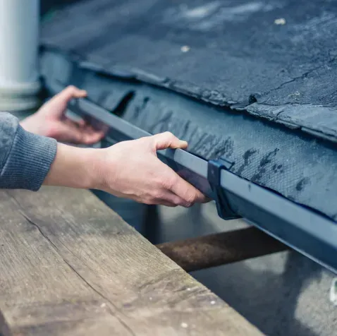A person is cleaning a gutter on a roof.