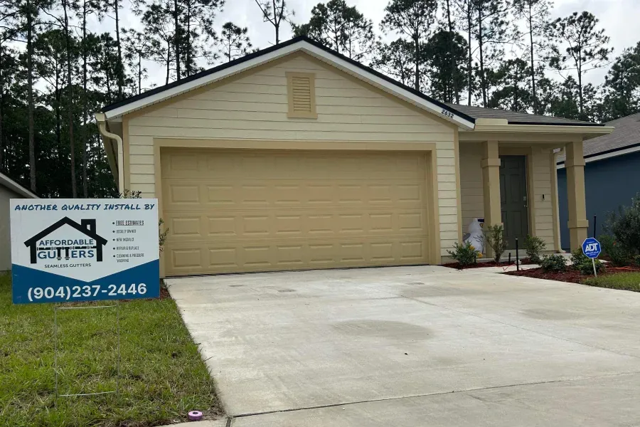 A house with a garage door and a sign in front of it.