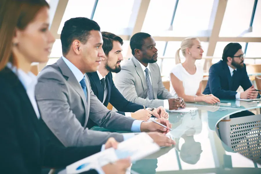 A group of business people are sitting at a table having a meeting.