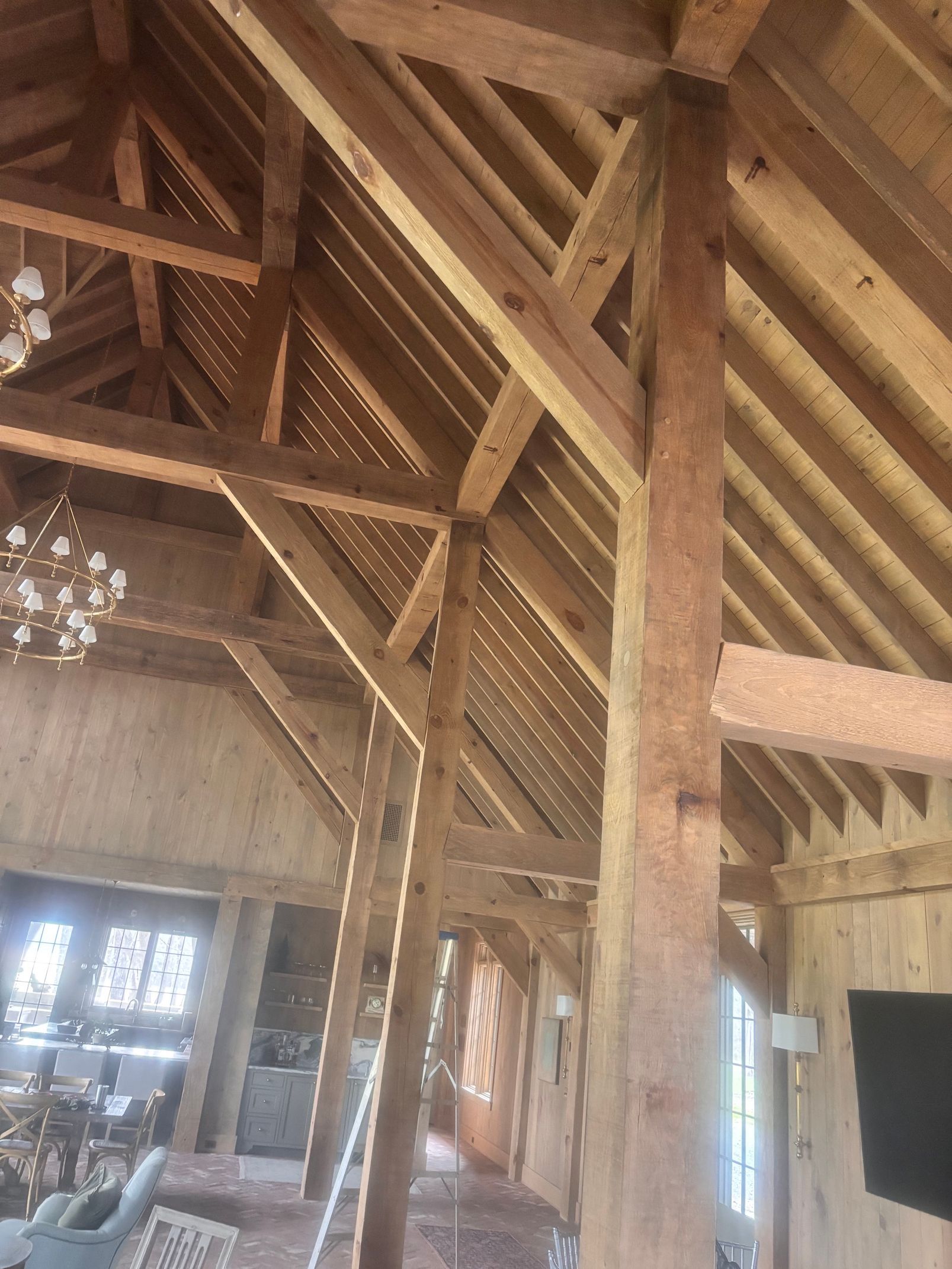 Interior of a wooden hall with exposed beams and a chandelier in warm light