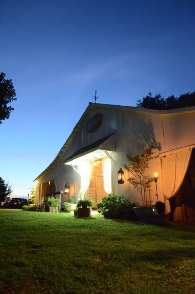Lit white tent with warm lights on a grassy lawn at dusk under a blue sky