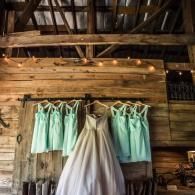 Mint and white dresses hanging inside a rustic wooden barn