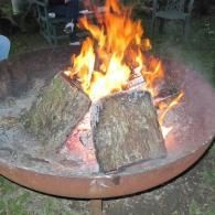 Logs burning in a metal fire pit outdoors.